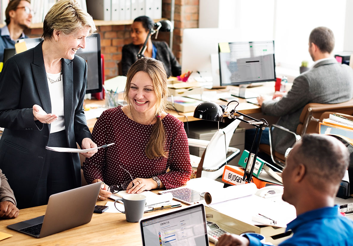 people in an office smiling and working with computers