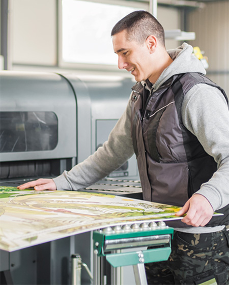 man feeding paper into large format printer