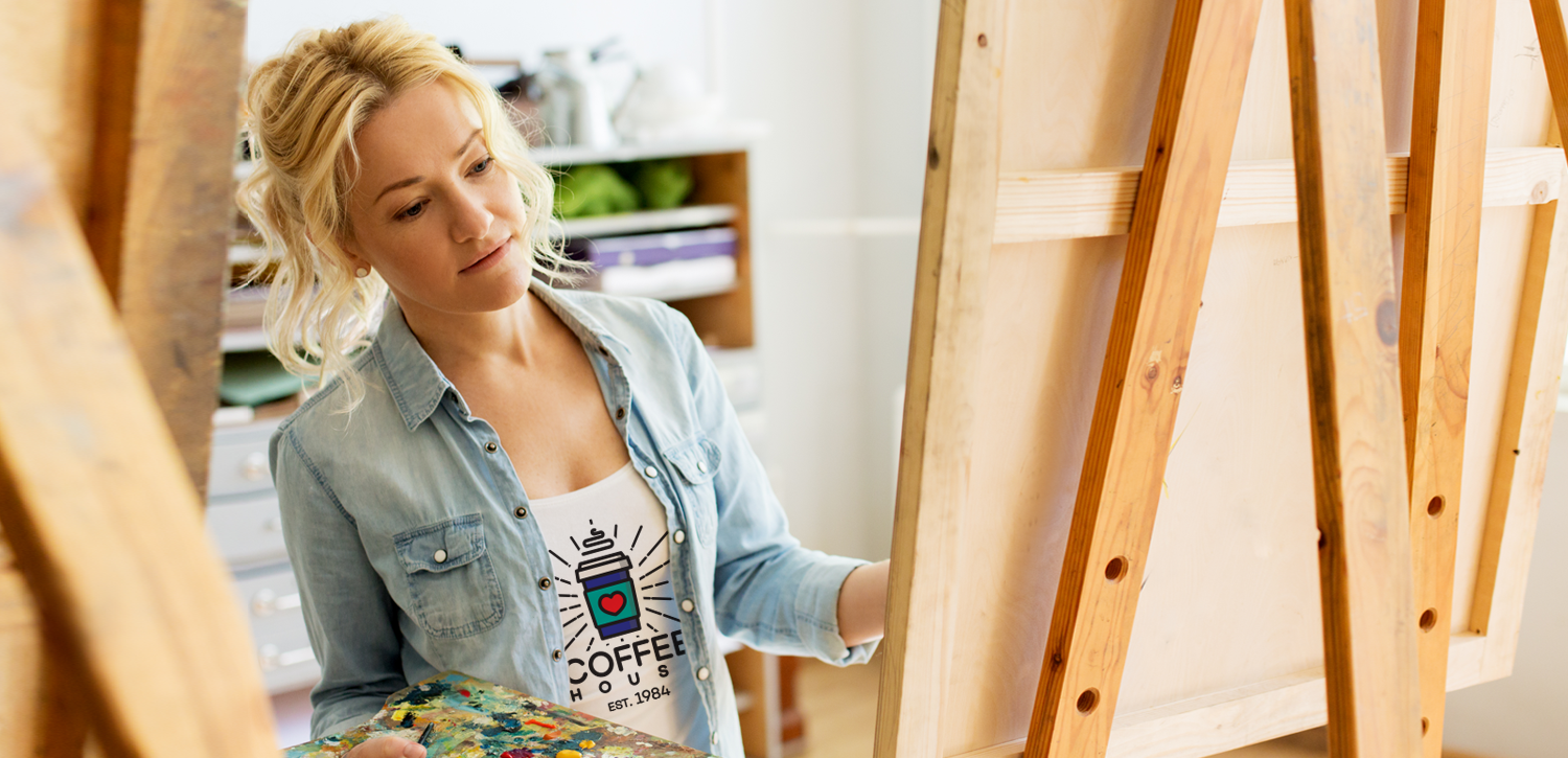 woman painting on canvas wearing logoed t-shirt