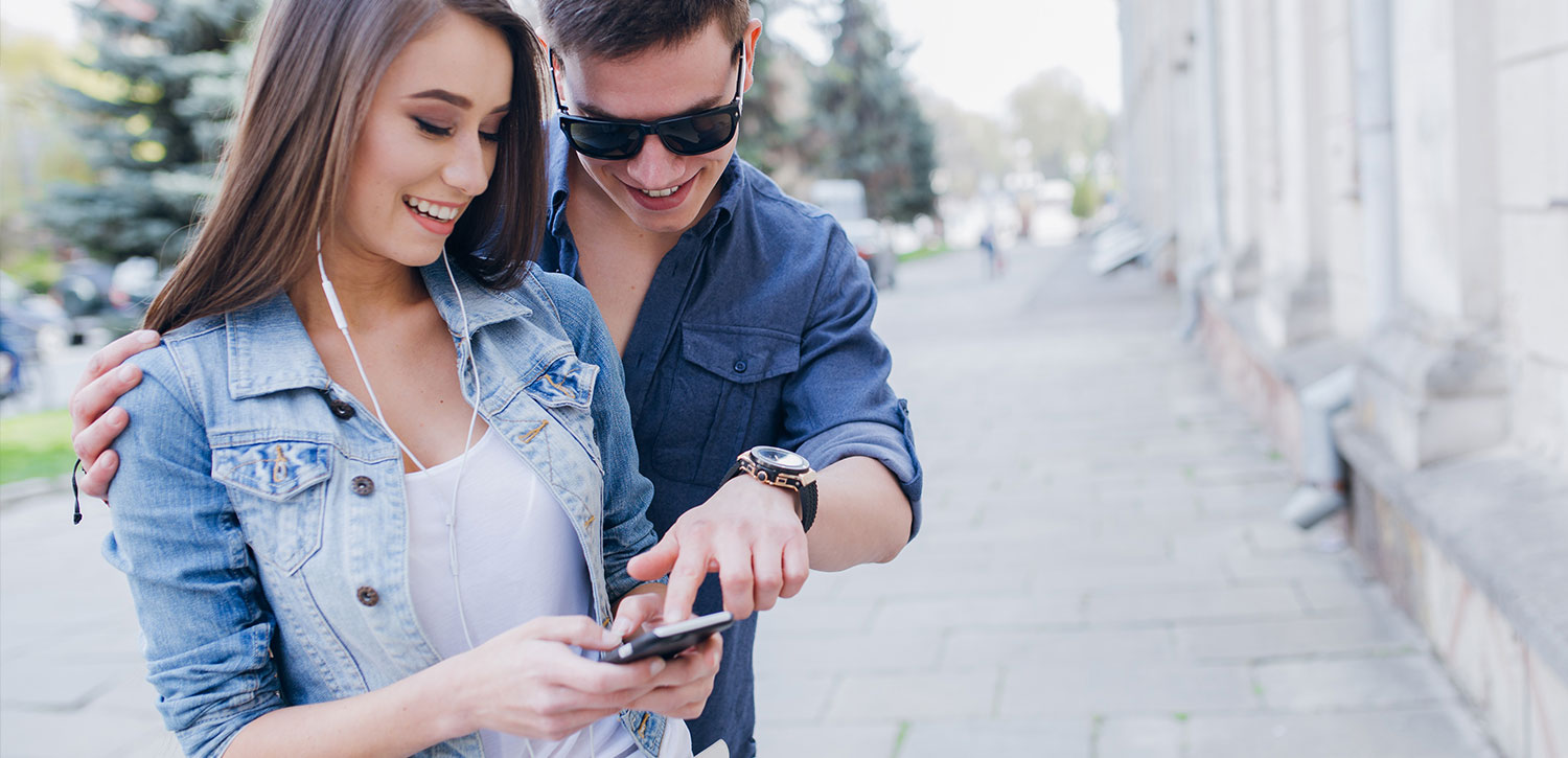 Smiling man pointing at a phone that a woman is holding